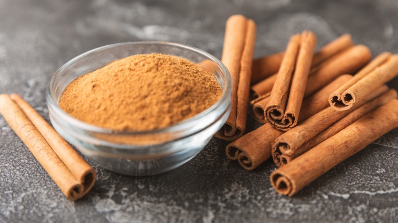 Bowl of ground cinnamon with cinnamon sticks