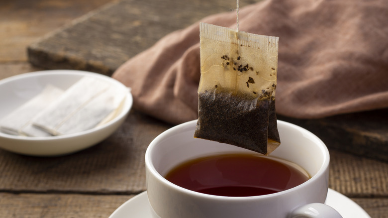 Tea bag hanging above cup of tea