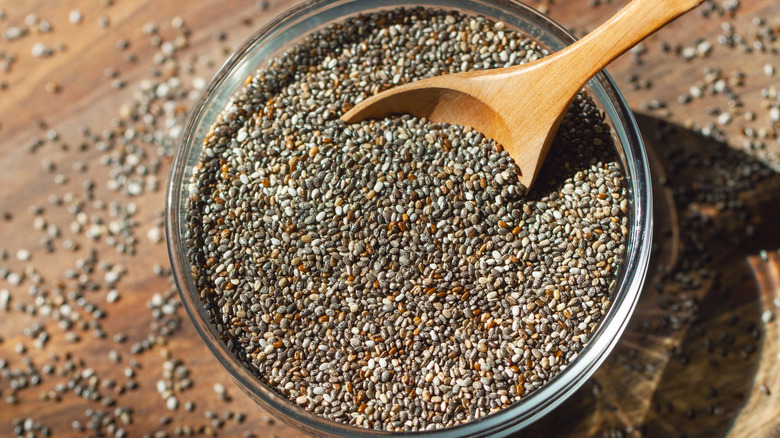 Glass container of chia seeds with wooden spoon