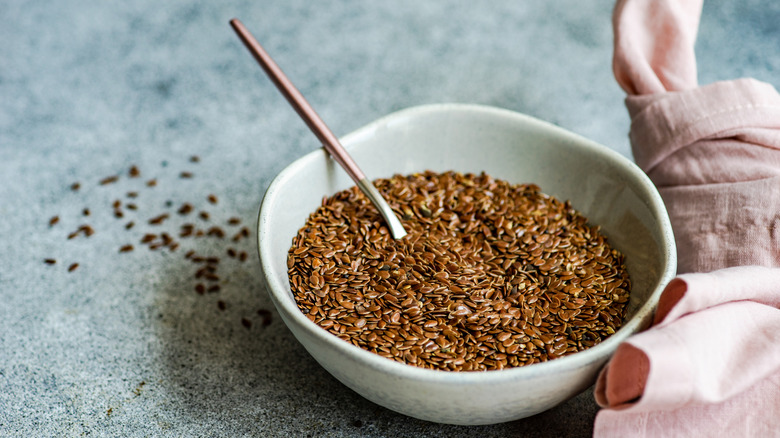 Bowl of whole flaxseed with spoon and fabric