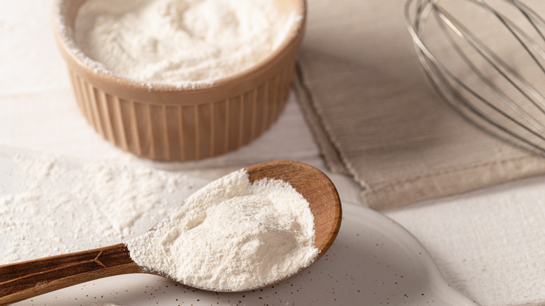 Spoonful of xanthan gum with beige bowl and whisk