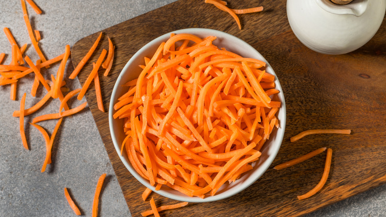 Bowl of shredded carrots on wooden platter