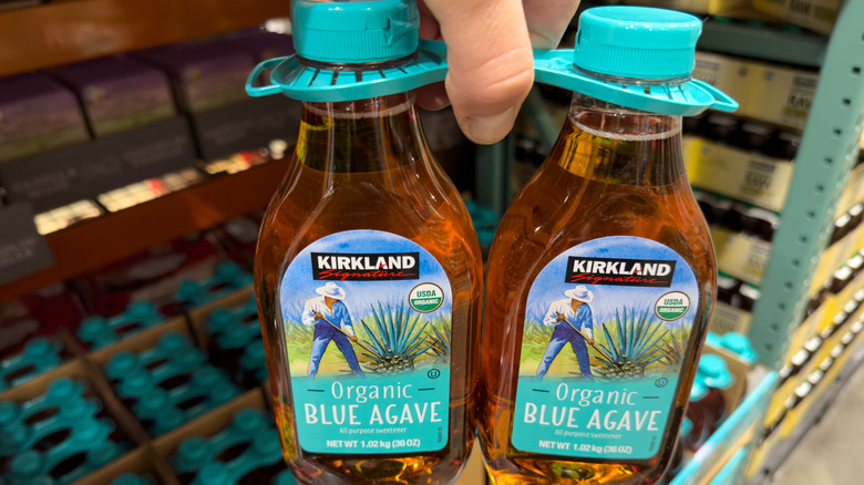 Hand holding two-pack of Kirkland brand blue agave syrup