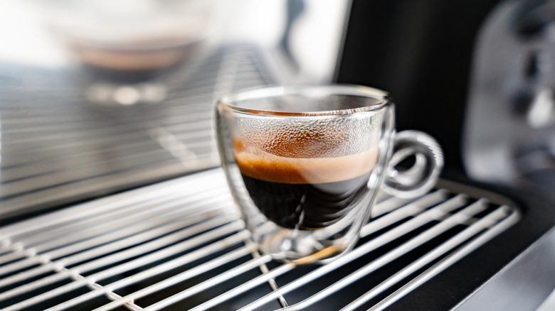 Shot of espresso in glass cup on espresso machine grate