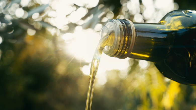 Close-up of olive oil being poured from bottle outdoors