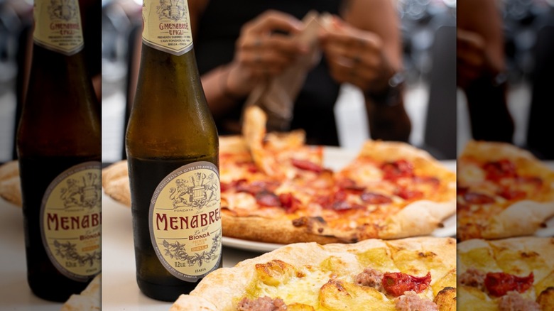 A bottle of Menabrea Bionda with two pizzas