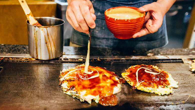 Street vendor cooking okonomiyaki on grill