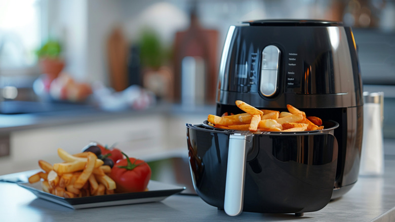 Air fryer on kitchen counter with the fryer basked full of fries