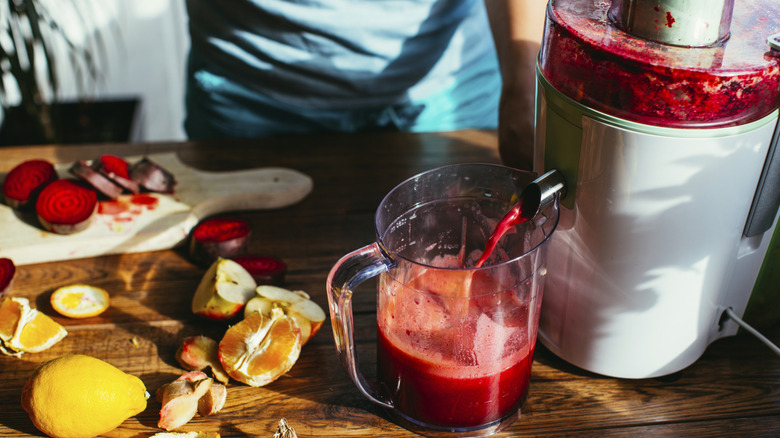Juicer juicing beets on wooden table
