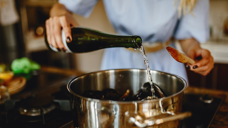 woman pouring wine into mussels