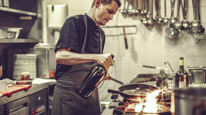 chef cooking with wine bottle