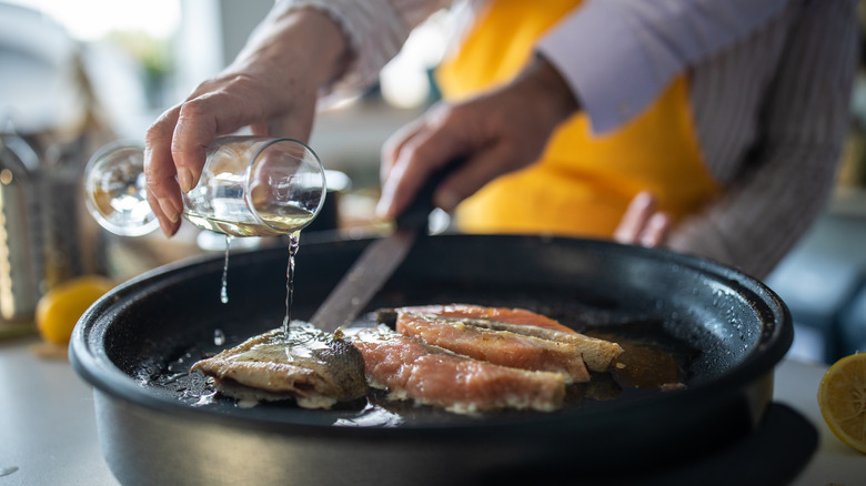 person pouring wine over fish