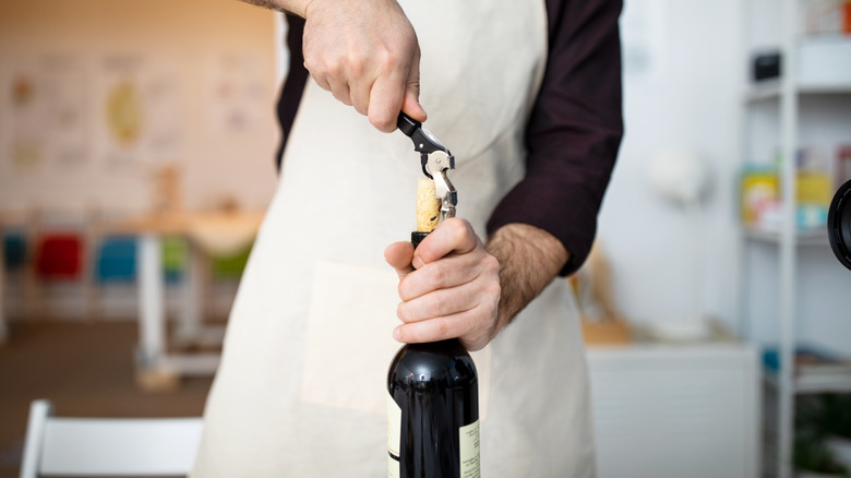 man opening wine bottle