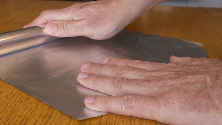 Hands on sheet of aluminum foil