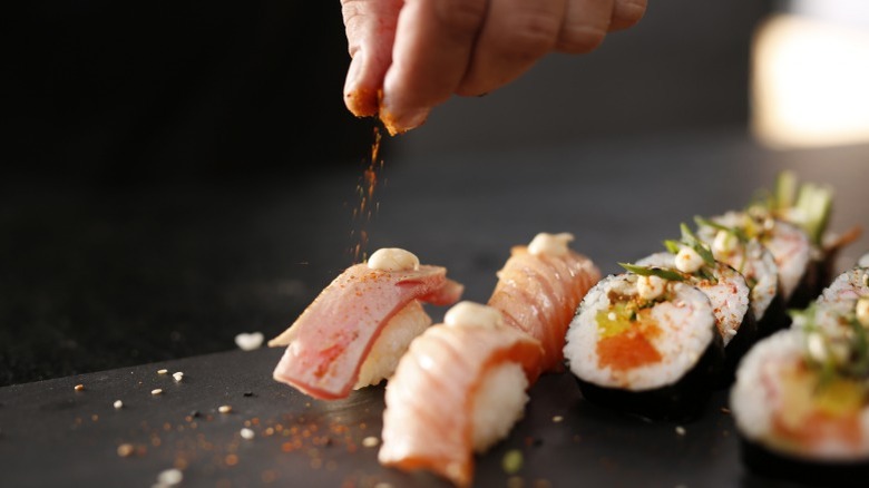 Hand sprinkling seasoning on nigiri