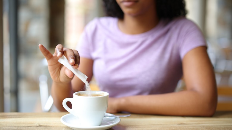 woman adding sugar coffee