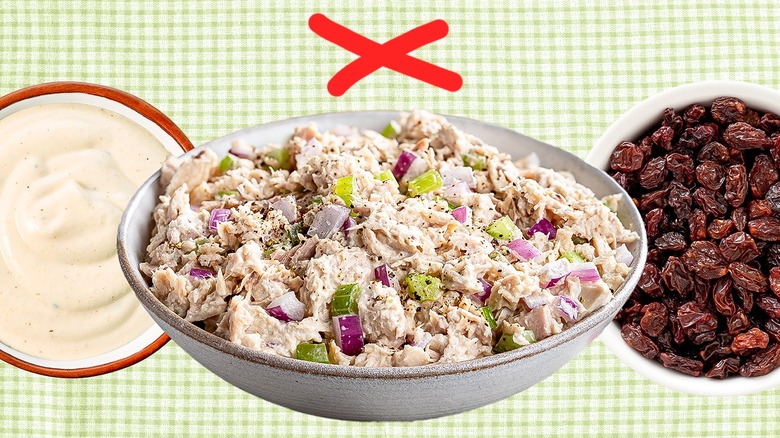 A bowl filled with tuna salad with a red x on top with a bowl of raisins and mayo on the side