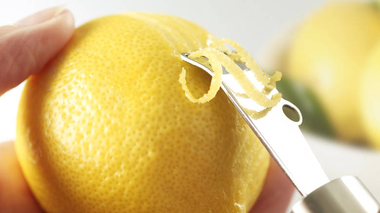 A closeup shows a person zesting a lemon.