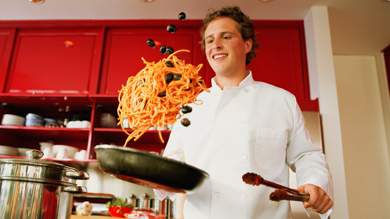 A chef tosses some pasta in the air.