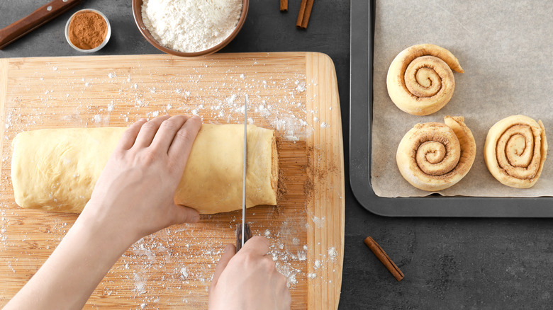 Person cutting cinnamon rolls