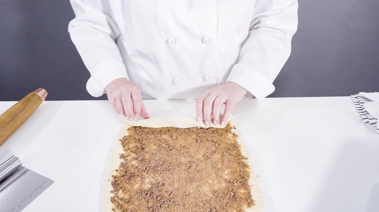 Person filling cinnamon rolls