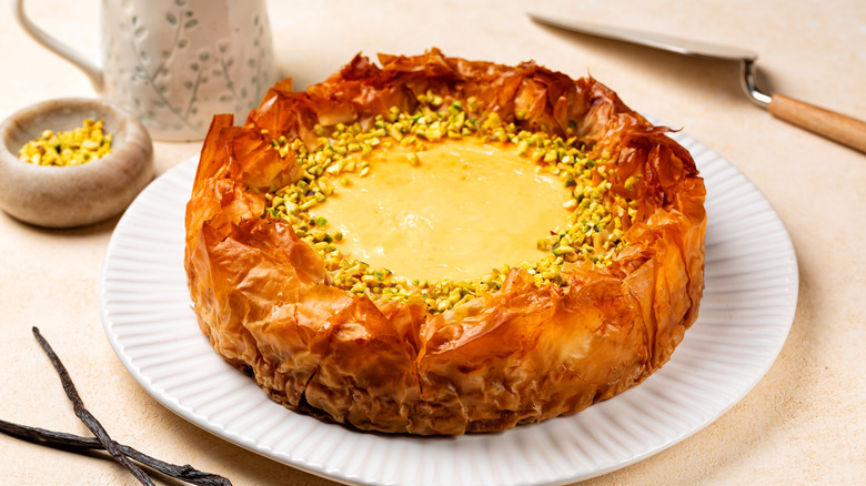 Baklava cheesecake on a plate with chopped pistachios scattered on top