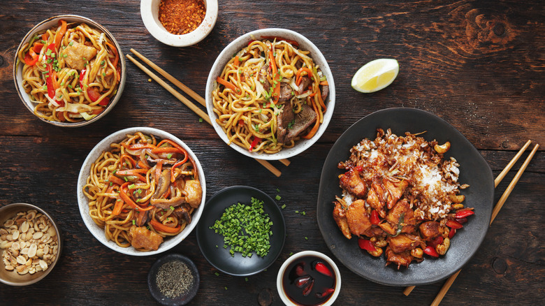 Top-down view of white bowls of Chinese dishes on wood table