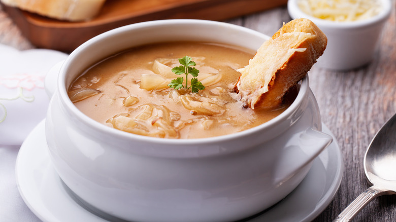 Close-up of French Onion soup and slice of bread in white bowl
