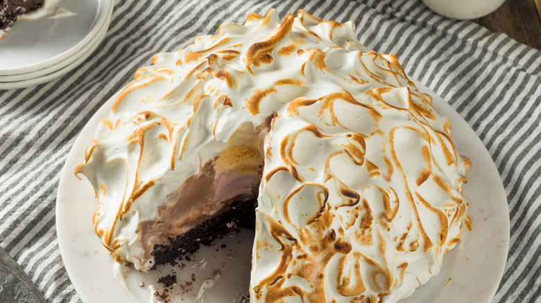 Golden brown Baked Alaska with a meringue shell, revealing layers of cake and ice cream inside