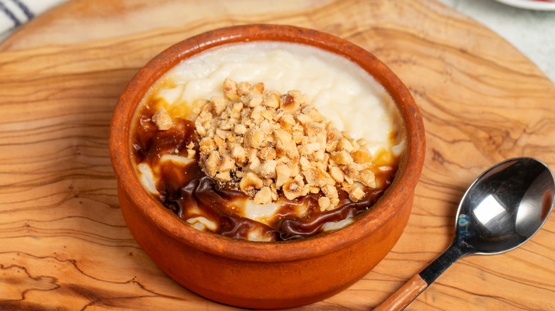 Rice pudding dessert topped with nuts on a wooden board ready to enjoy