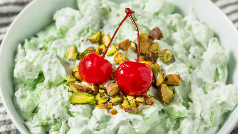 Watergate salad featuring a light green, creamy mixture of pistachio pudding, pineapple, marshmallows, and nuts