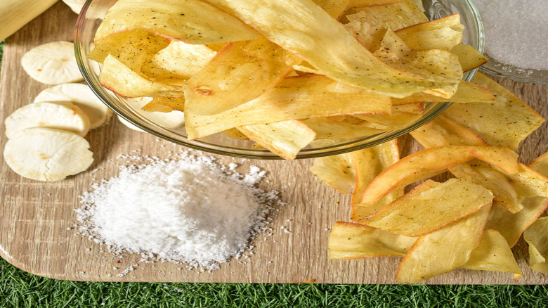 Cassava next to glass bowl of cassava chips