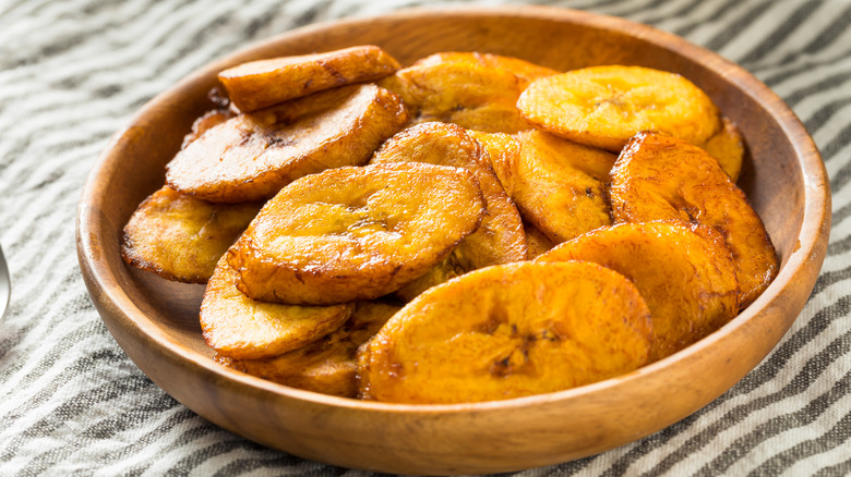 Wooden bowl of fried plantains on cloth