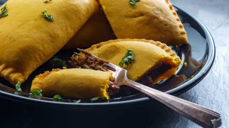 beef patties on black plate with one split by a fork