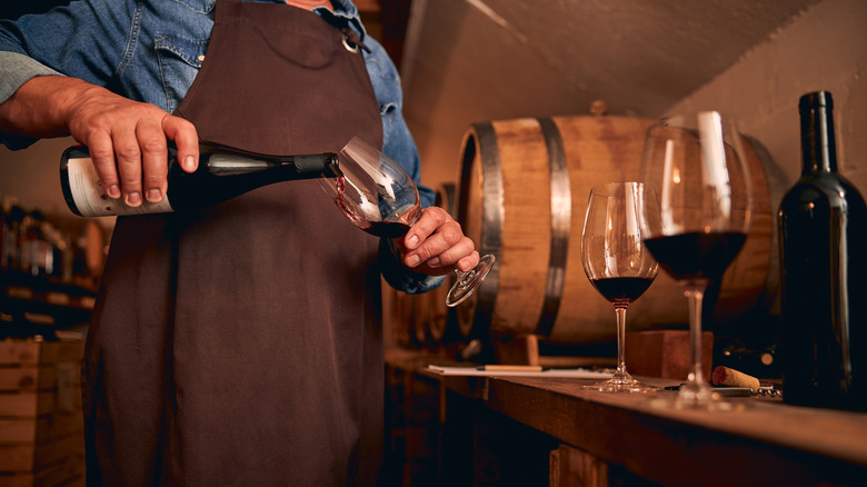 Winemaker pouring wine in cellar