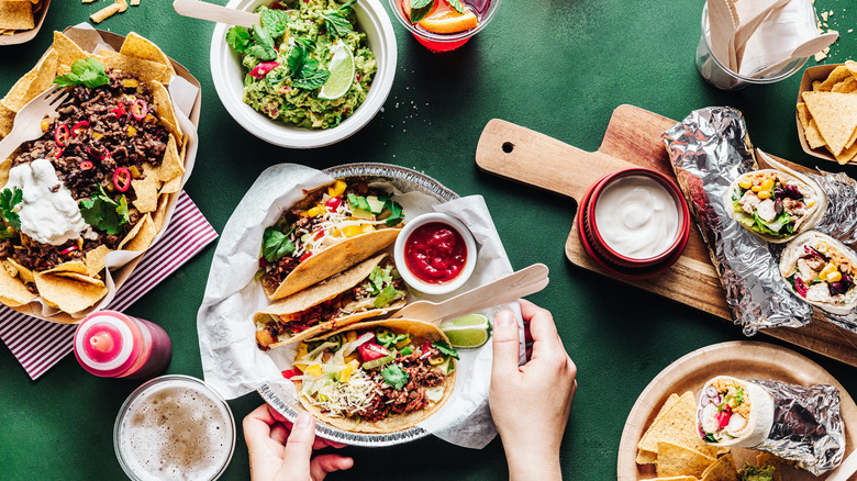 Tacos with sauces and salsa on table