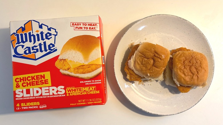 Two White Castle frozen chicken cheese sliders on plate next to box of sliders