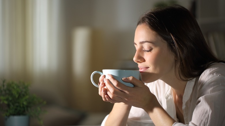 Woman smelling cup of coffee