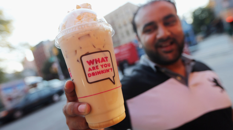 a man holding a iced beverage from dunkin'