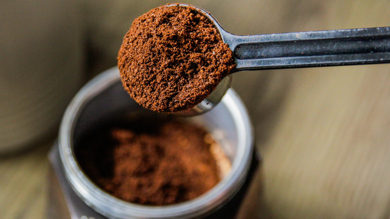 Coffee grounds being taken out of jar with spoon