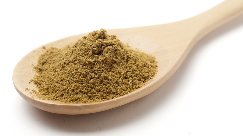 Ground cumin on wooden spoon