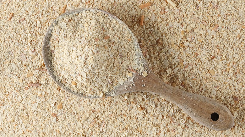 Pile of nutritional yeast with wooden scoop on top