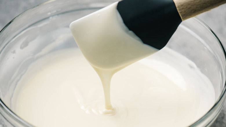 Condensed milk dripping off silicone spatula into a bowl