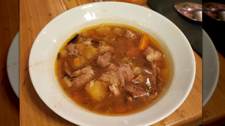 Meat and vegetable soup in white bowl