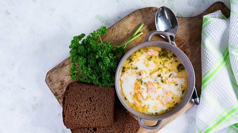 Salmon soup on wooden board with rye bread