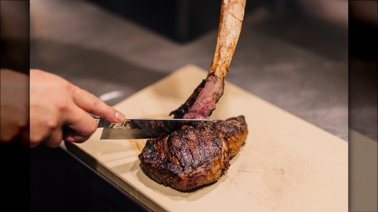 hand carving grilled bone-in steak