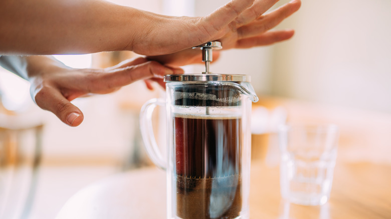 hand pushing down on French press