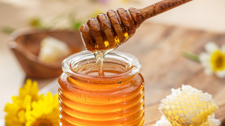 Wooden dipper over pot of honey