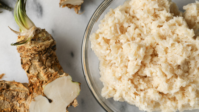 Prepared horseradish in bowl next to horseradish root