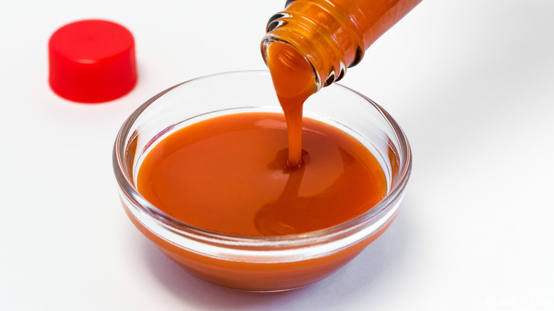 Pouring hot sauce from bottle into bowl